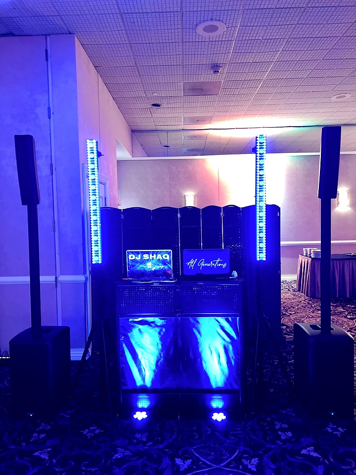 Illuminated DJ setup with speakers and vertical lighting at a 2025 company holiday party.