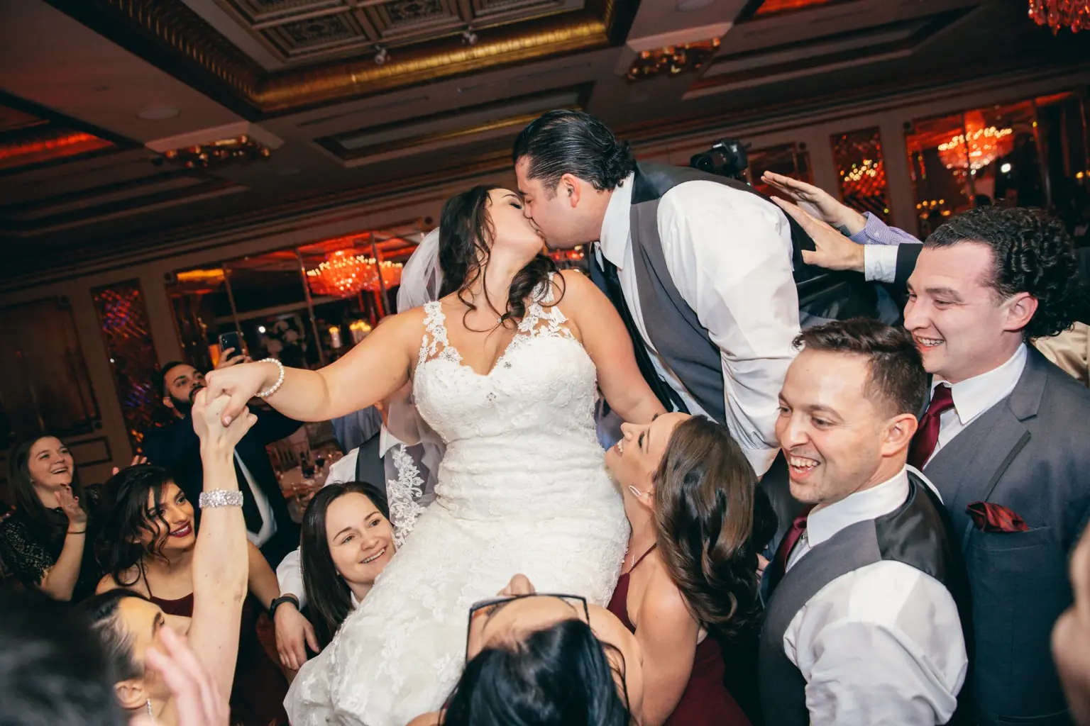 Newlyweds share a kiss surrounded by friends on the dance floor.